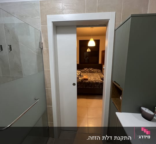 דלת הזזה בחדר אמבטיה עם ארון וכיור